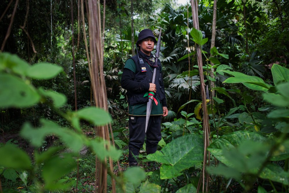 Marcelo Lucitante, a member of the Cofan indigenous guard, in the Amazon rainforest in northern Ecuador, holds a spear while on patrol near his village of Sinangoe, on April 21, 2022. Indigenous guards patrol their ancestral lands to keep illegal gold miners, poachers and hunters at bay. Thomson Reuters Foundation/Fabio Cuttica